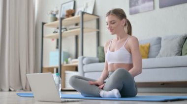 Yoga Mat 'teyken laptopta video çağrısı yapan kadın.