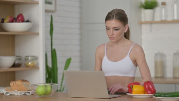 Atletisk kvinna som arbetar på laptop i köket — Stockvideo