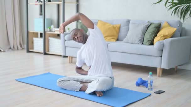 Ung afrikansk man mediterar på yogamattan hemma — Stockvideo