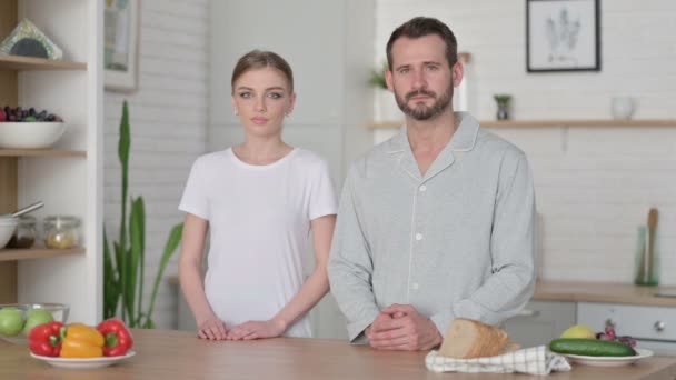 Mujer joven y hombre mirando a la cámara en la cocina — Vídeo de stock