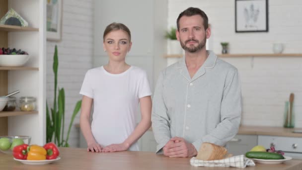 Jovem mulher e homem sorrindo para a câmera na cozinha — Vídeo de Stock