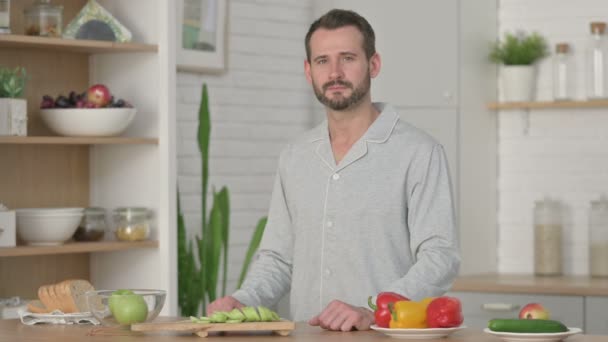 Joven sonriendo a la cámara mientras está de pie en la cocina — Vídeos de Stock