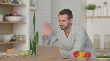 Genç adam Mutfaktaki Laptop 'ta video görüşmesi yapıyor.