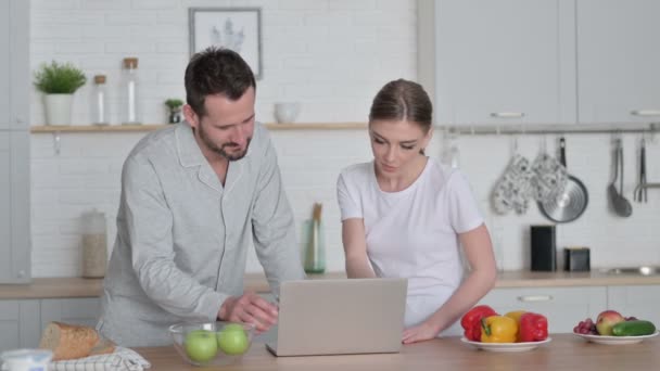 Женщина и мужчина работают над ноутбуком на кухне — стоковое видео