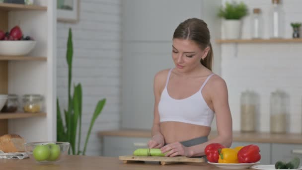 Gezonde vrouw snijden komkommer terwijl staande in de keuken — Stockvideo