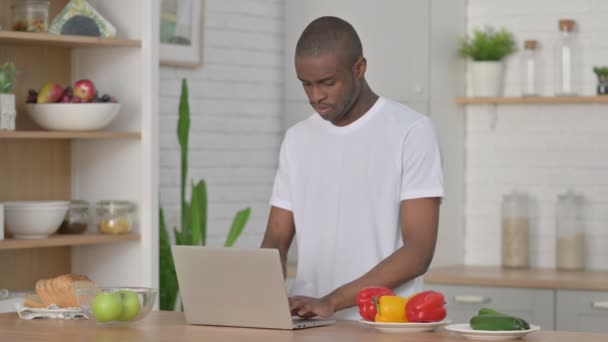 Uomo africano atletico che lavora sul computer portatile in cucina — Video Stock