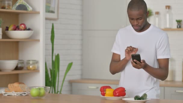 Sportowy Afrykanin robi zdjęcia owoców na smartfonie w kuchni — Wideo stockowe
