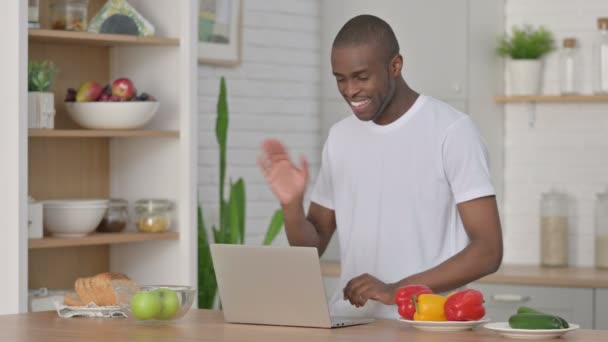 Atlético Africano Homem fazendo chamada de vídeo no laptop na cozinha — Vídeo de Stock