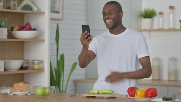 Αφρικανός κάνει βιντεοκλήση στο Smartphone, ενώ στέκεται στην κουζίνα — Αρχείο Βίντεο