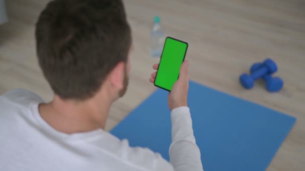 Visão traseira do homem usando Smartphone com Chroma Key Screen na esteira de Yoga — Vídeo de Stock