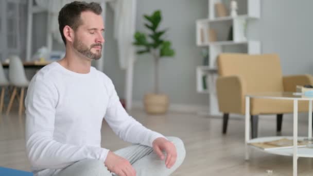 Man mediterar på yogamattan hemma — Stockvideo