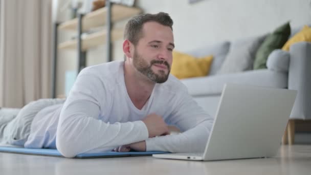 Detailní záběr Man dělá video hovor na notebooku, zatímco na Jóga Mat — Stock video