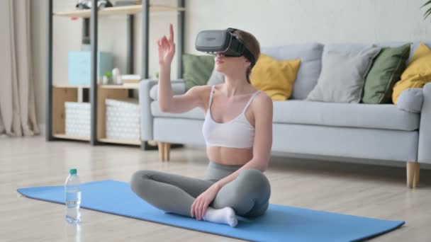 Женщина, использующая виртуальную реальность, сидит на коврике для йоги — стоковое видео