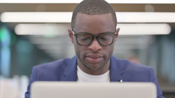 Empresario africano con computadora portátil sonriendo a la cámara — Vídeo de stock