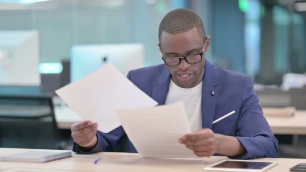 Un homme d'affaires africain célèbre son succès en lisant des documents — Video