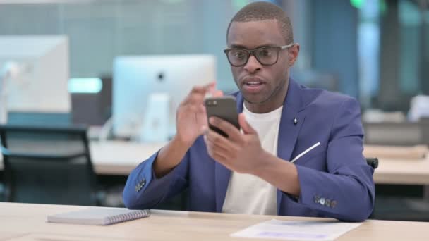 Uomo d'affari africano che reagisce alla perdita su Smartphone in ufficio — Video Stock