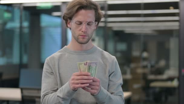 Porträt eines jungen Geschäftsmannes, der Dollars zählt und gibt — Stockvideo