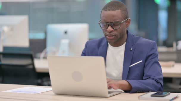 Joven empresario africano con portátil que tiene dolor de cuello — Vídeo de stock