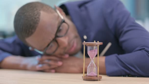 Afrikanischer Geschäftsmann wartet und blickt auf Sanduhr — Stockvideo