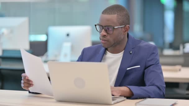 Geschäftsmann mit Laptop liest Dokumente im Büro — Stockvideo