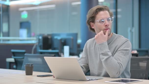 Junger Geschäftsmann mit Laptop macht sich Sorgen bei der Arbeit — Stockvideo