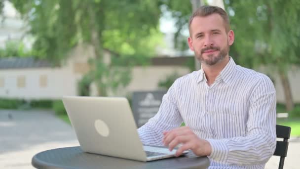 Palce dolů podle středověkého muže s notebookem v venkovní kavárně — Stock video