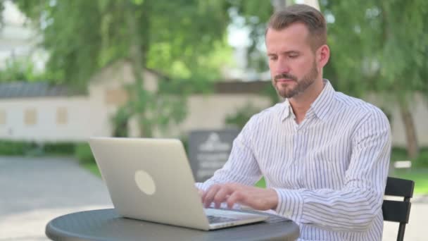 Uomo di mezza età che lavora sul computer portatile in caffè all'aperto — Video Stock