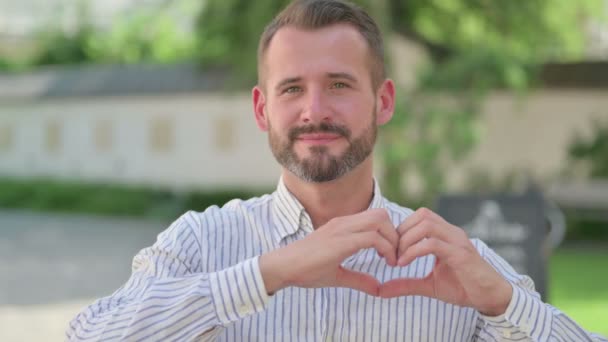 Outdoor Portret van de Middeleeuwen Man toont hart teken door handen — Stockvideo