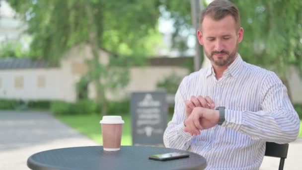 Medelålders man använder Smartwatch i Outdoor Cafe — Stockvideo