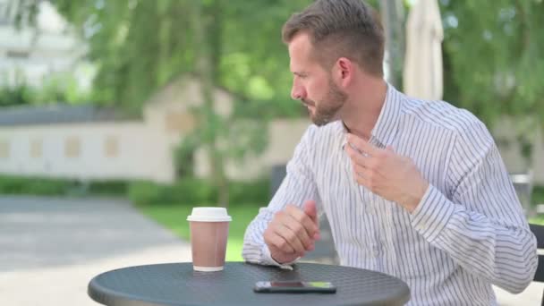 Hombre de mediana edad sintiéndose preocupado mientras espera en el café al aire libre — Vídeos de Stock