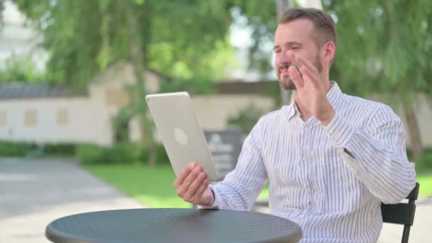 Středověký muž dělat video hovor na tabletu v venkovní kavárně — Stock video