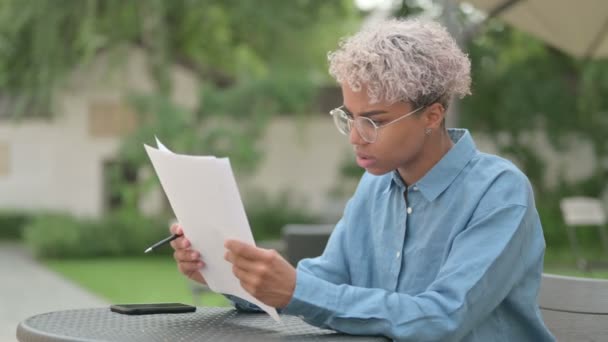 Joven mujer africana teniendo pérdida mientras lee documentos — Vídeos de Stock