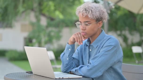 Jonge Afrikaanse vrouw denken en werken op laptop in Outdoor Cafe — Stockvideo