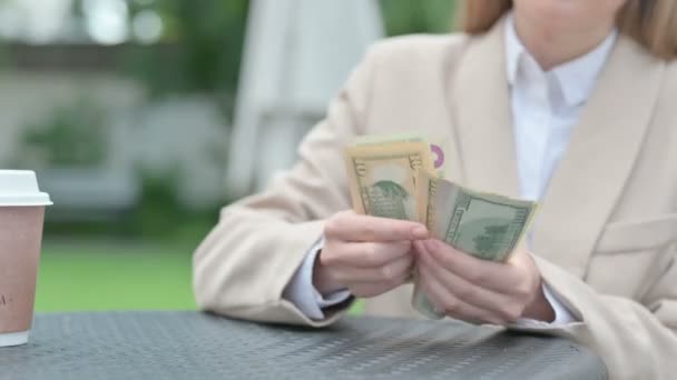 Крупним планом молода бізнес-леді підраховують долари у відкритому кафе — стокове відео