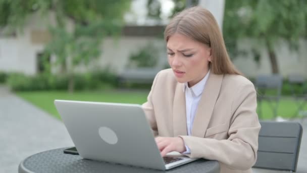 Молодая предпринимательница кричит во время работы над ноутбуком в открытом кафе — стоковое видео
