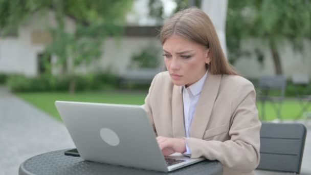Молодая предпринимательница чувствует гнев, работая на ноутбуке в открытом кафе — стоковое видео