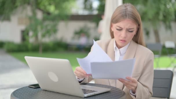 Jonge zakenvrouw met laptop viert tijdens het lezen van documenten — Stockvideo