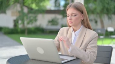 Laptop 'u olan genç iş kadını açık kafede boyun ağrısı çekiyor.