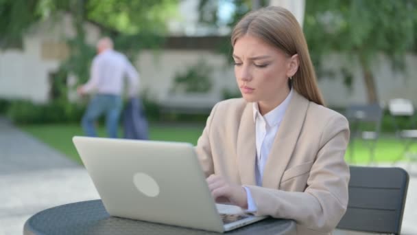 Giovane imprenditrice pensare e lavorare sul computer portatile in Outdoor Cafe — Video Stock