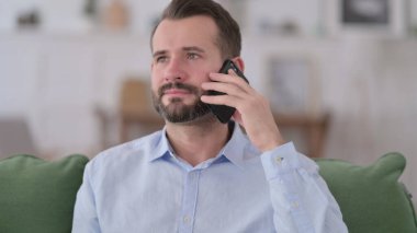 Meşgul genç adam telefonda konuşuyor. 