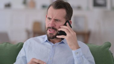 Kızgın genç adam telefonda konuşuyor.