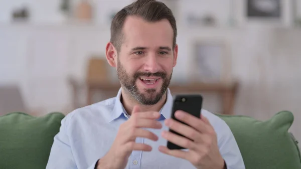 Young Man Celebrating on Smartphone at Home — Stock Photo, Image