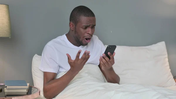 Falha, Jovem Africano Reagindo à Perda no Smartphone na Cama — Fotografia de Stock
