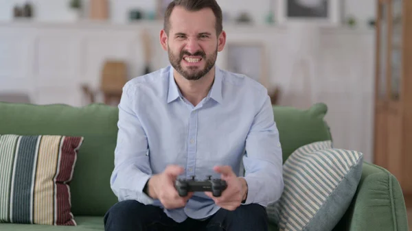 Junger Mann verliert bei Videospiel auf Sofa — Stockfoto