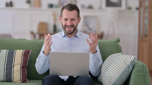 Giovane uomo di successo con computer portatile che celebra sul divano — Foto Stock