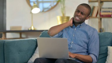 Dizüstü bilgisayar: Genç Afrikalı, Kanepede Boyun Ağrısı Olan Adam 