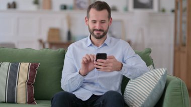 Kanepede Akıllı Telefon Kullanan Ciddi Genç Adam 