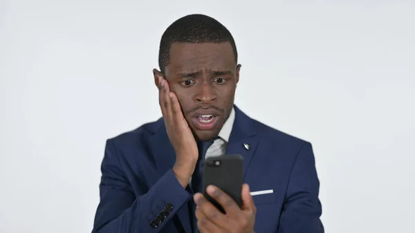 Empresario africano reaccionando al fracaso en el teléfono inteligente, fondo blanco —  Fotos de Stock