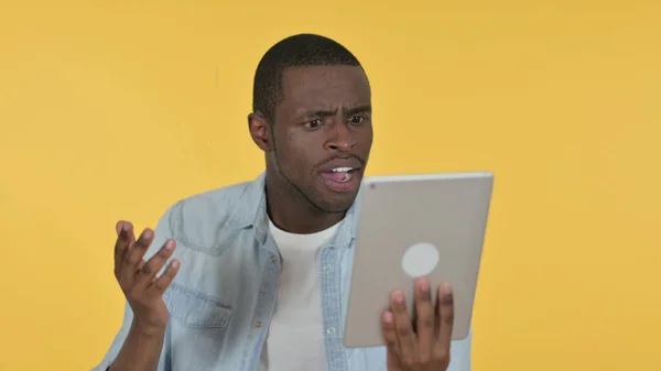 Fiatal afrikai férfi reagál a veszteség tabletta, sárga háttér — Stock Fotó