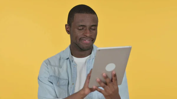 Młody Afrykanin za pomocą tabletu cyfrowego, żółte tło — Zdjęcie stockowe